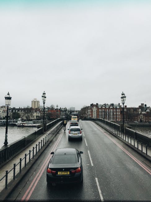A view of a wide city bridge from above, with three lanes of traffic moving in the same direction across the River Thames in Battersea. The roadway is lined with traditional black iron lamp posts on b